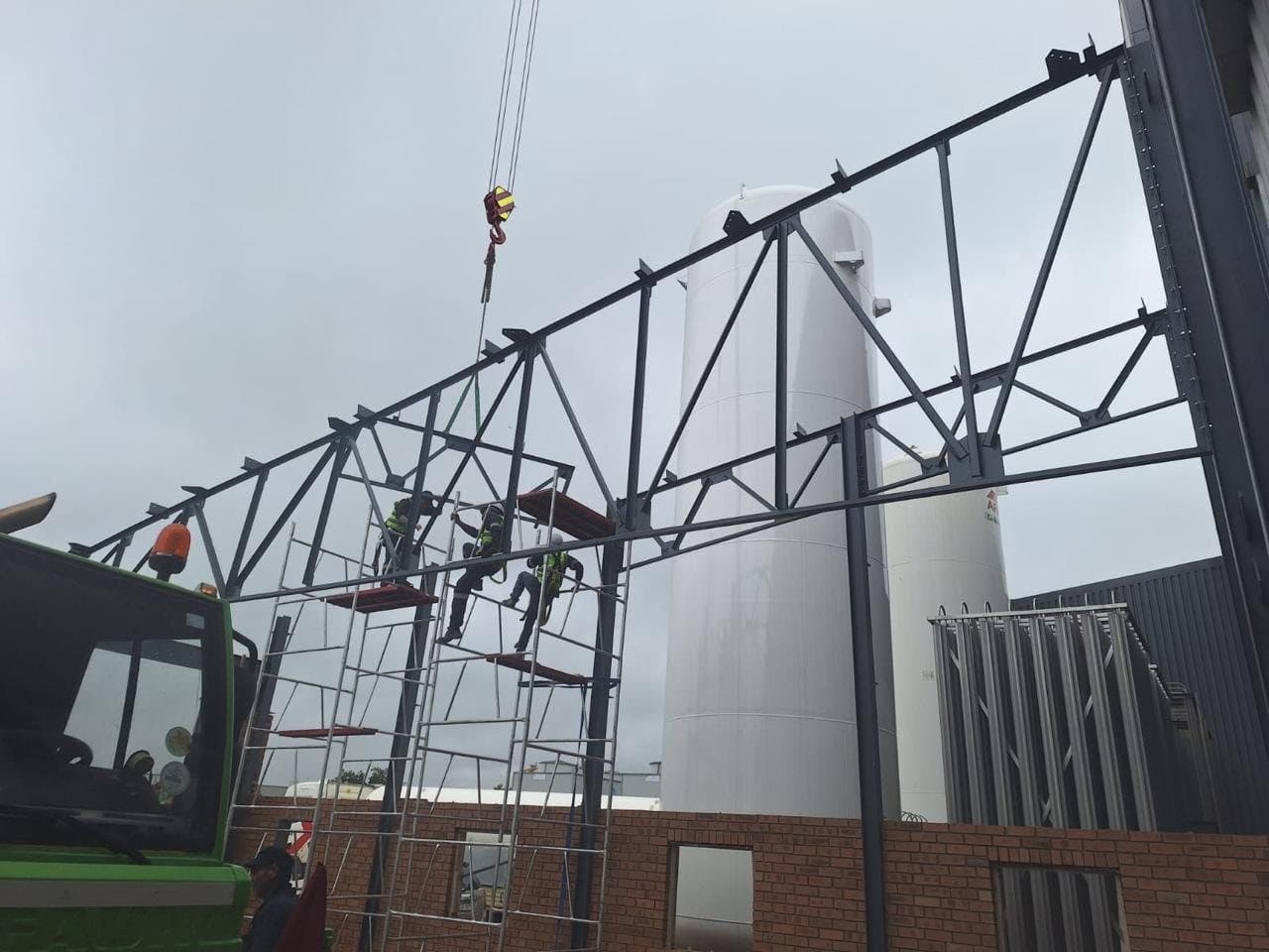 Truss being lifted into position by crane inside a plant